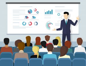 Image of an executive giving a powerpoint presentation in front of an audience